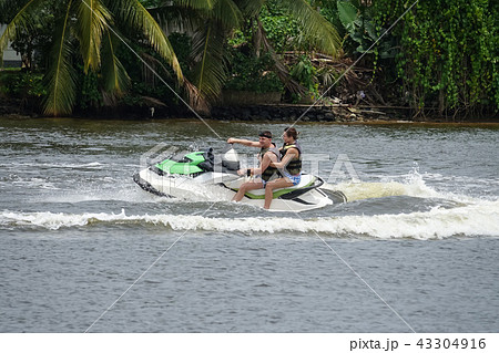 Happy young couple having fun riding on a jet ski Happy young couple having fun riding on a jet ski 43304916