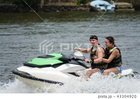 Happy young couple having fun riding on a jet ski Happy young couple having fun riding on a jet ski 43304920