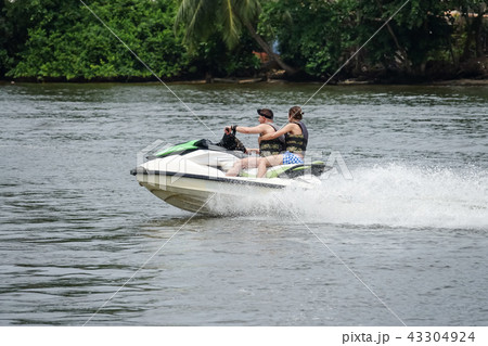 Happy young couple having fun riding on a jet ski Happy young couple having fun riding on a jet ski 43304924