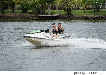 Happy young couple having fun riding on a jet ski Happy young couple having fun riding on a jet ski 43304925
