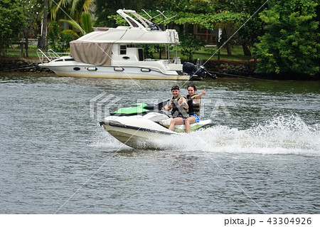 Happy young couple having fun riding on a jet ski Happy young couple having fun riding on a jet ski 43304926