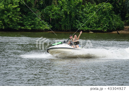 Happy young couple having fun riding on a jet ski Happy young couple having fun riding on a jet ski 43304927