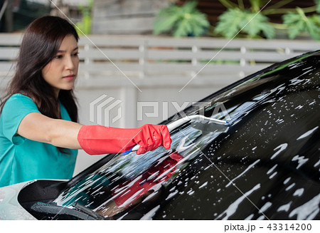 woman using squeegee to washing windshield of car 43314200