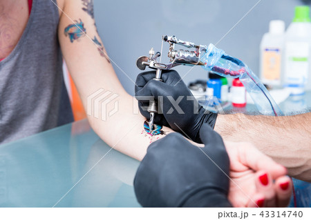 Close-up of the hands of a skilled tattoo artist wearing black gloves 43314740