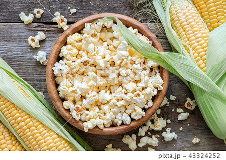 Prepared popcorn in wooden bowl, corncobs on table Prepared popcorn in wooden bowl, corncobs on table 43324252