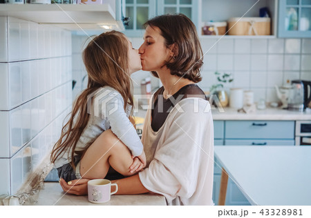 Mom kisses her little daughter in the kitchen 43328981