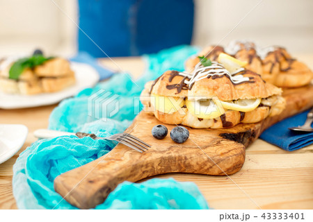 Close-up chef decorating sweet croissant on cooking table. Close-up chef decorating sweet croissant on cooking table. 43333401