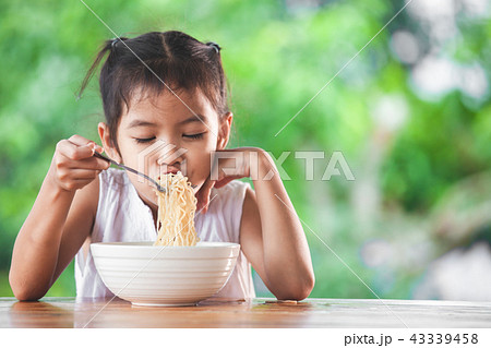 asian child girl eating delicious instant noodles 43339458