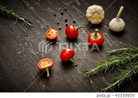spicy red peppers, garlic and rosemary on a black wooden table 43339959