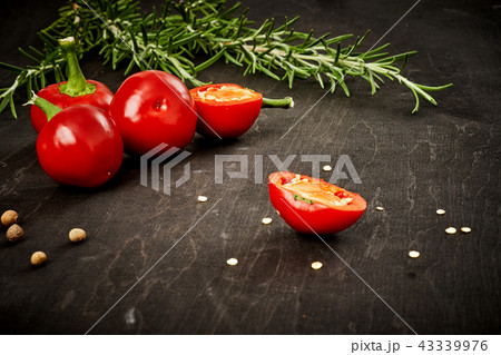 fresh and spicy red peppers and rosemary on a black table fresh and spicy red peppers and rosemary on a black table 43339976