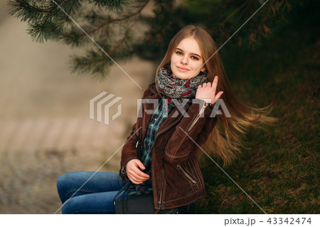 A beautiful girl is walking along the embankment. Blond hair and brown jacket. Spring 43342474