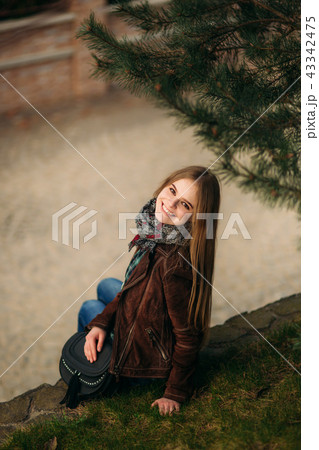 A beautiful girl is walking along the embankment. Blond hair and brown jacket. Spring A beautiful girl is walking along the embankment. Blond hair and brown jacket. Spring 43342475