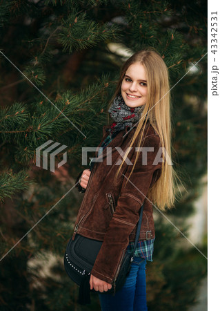 Blond girl walking in the park. Posing to the photographer. 43342531