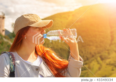 Woman drinking water in summer sunlight Woman drinking water in summer sunlight 43349334