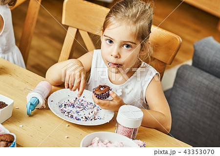 girl in a white dress decorates and eats a delicious cupcakes 43353070
