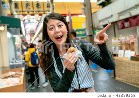 asian woman holding the dessert in one hand. 43359258