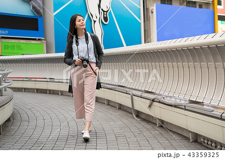 asian female holding a camera on the bridge. asian female holding a camera on the bridge. 43359325