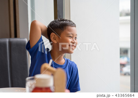 Cute asian boy seat at window eating food 43365664