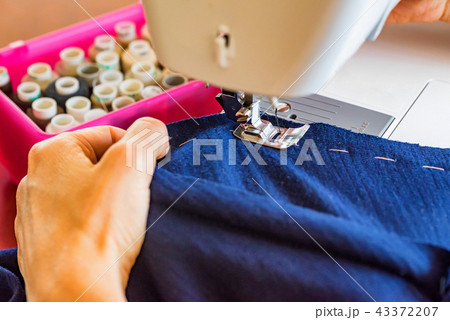 Dressmaker or seamstress works using sewing machine 43372207