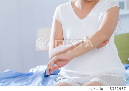young woman applying beauty lotion on her elbow 43372987