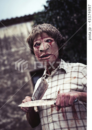 scary disfigured man sharpening his knives 43374997