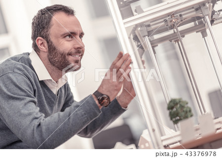Smiling adult positive man touching 3D printer Smiling adult positive man touching 3D printer 43376978