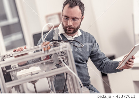 Bearded adult man adjusting 3D printers components 43377013