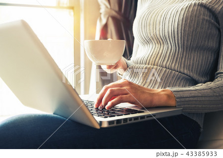 womman using laptop and typing and holding coffee  43385933