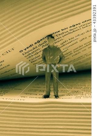 Figurine standing inside the pages of a book Figurine standing inside the pages of a book 43392391
