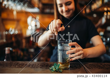 Female barman mixing at the bar counter in pub 43400114