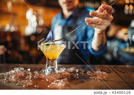 Male bartender prepares alcoholic coctail with ice Male bartender prepares alcoholic coctail with ice 43400116