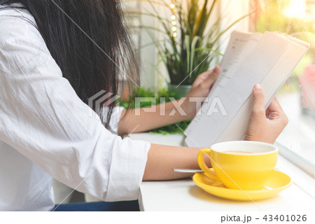 Asian woman reading book beside coffee shop window Asian woman reading book beside coffee shop window 43401026