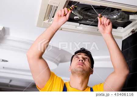 Repairman repairing ceiling air conditioning unit Repairman repairing ceiling air conditioning unit 43406116