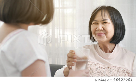 Little Asian girl give a glass of water to senior 43407035