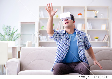 Man with virtual reality glasses playing at home Man with virtual reality glasses playing at home 43407519
