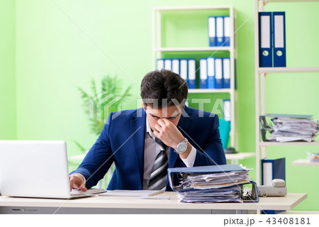 Businessman unhappy with excessive work sitting in the office  43408181