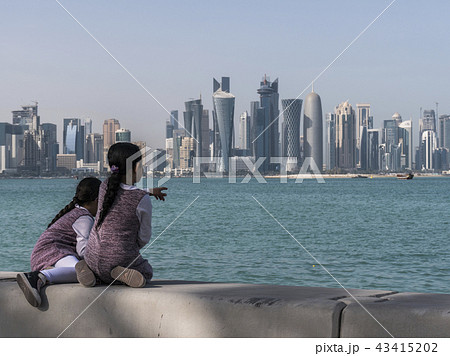 Two Arabian Middle Easter Little Child Girls Sitting on Corniche Broadway and Looking on the Doha 43415202