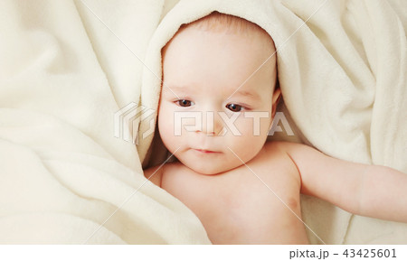 cute baby lying in bed covered with soft blanket cute baby lying in bed covered with soft blanket 43425601