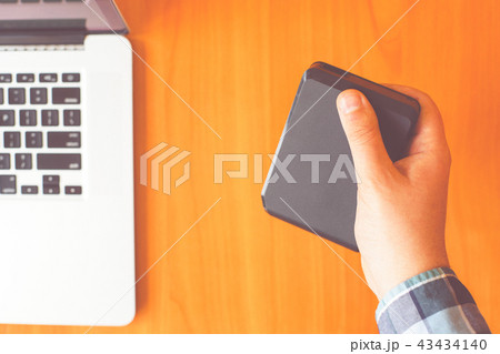 Man holds portable external hard drive.  43434140