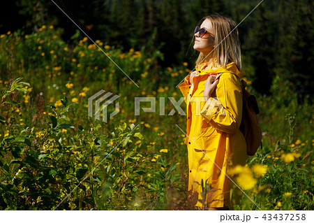 stylish hipster woman in yellow raincoat traveler with backpack on top of mountains, travel concept stylish hipster woman in yellow raincoat traveler with backpack on top of mountains, travel concept 43437258