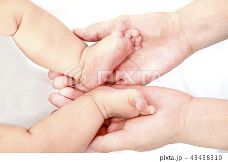 赤ちゃんの小さな両足を包むお母さんの大きな両手のアップ。母性、愛情、幸せ、育児、健康のイメージ 赤ちゃんの小さな両足を包むお母さんの大きな両手のアップ。母性、愛情、幸せ、育児、健康のイメージ 43438310