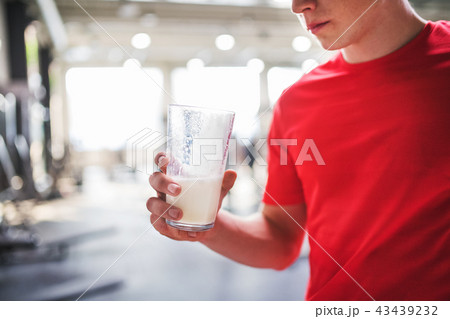 Young man in gym holding a glass of protein drink. Copy space. Young man in gym holding a glass of protein drink. Copy space. 43439232