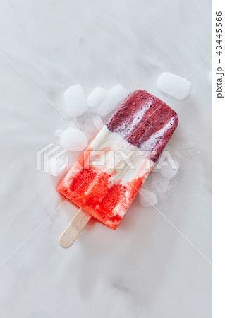 Vanilla berry sorbet on a stick with ice slices on a gray marble background with copy space. Top Vanilla berry sorbet on a stick with ice slices on a gray marble background with copy space. Top 43445566