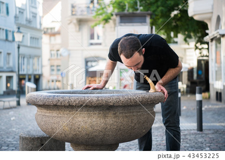 Caucasian young man preparing to drinking water from the fountain. Caucasian young man preparing to drinking water from the fountain. 43453225