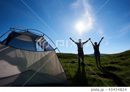 Rear view of pair raised their hands up to sunlight on green meadow Rear view of pair raised their hands up to sunlight on green meadow 43454824