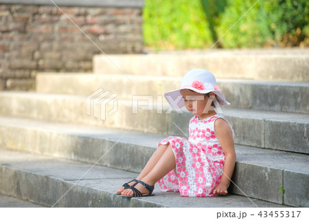 girl wearing white hat  sitting on stairs 43455317