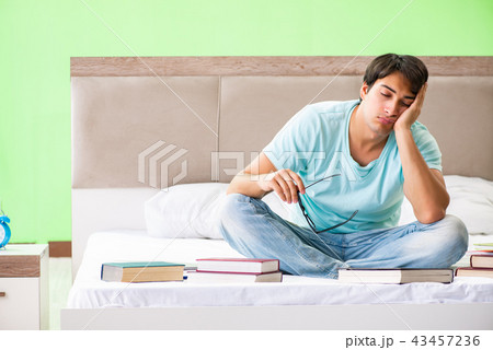 Student preparing for exams at home in bedroom sitting on the be 43457236