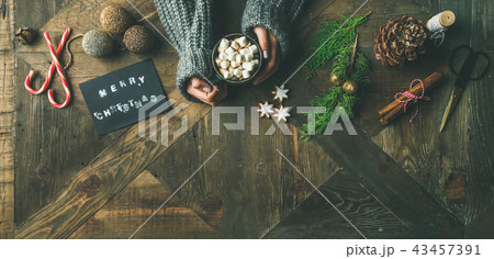 Flat-lay of greeting card, glittering toy, woman's hands holding mug 43457391