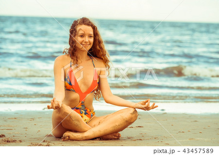 Young woman practices yoga on the beach in summer. 43457589