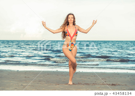 Young woman practices yoga on the beach in summer. Young woman practices yoga on the beach in summer. 43458134